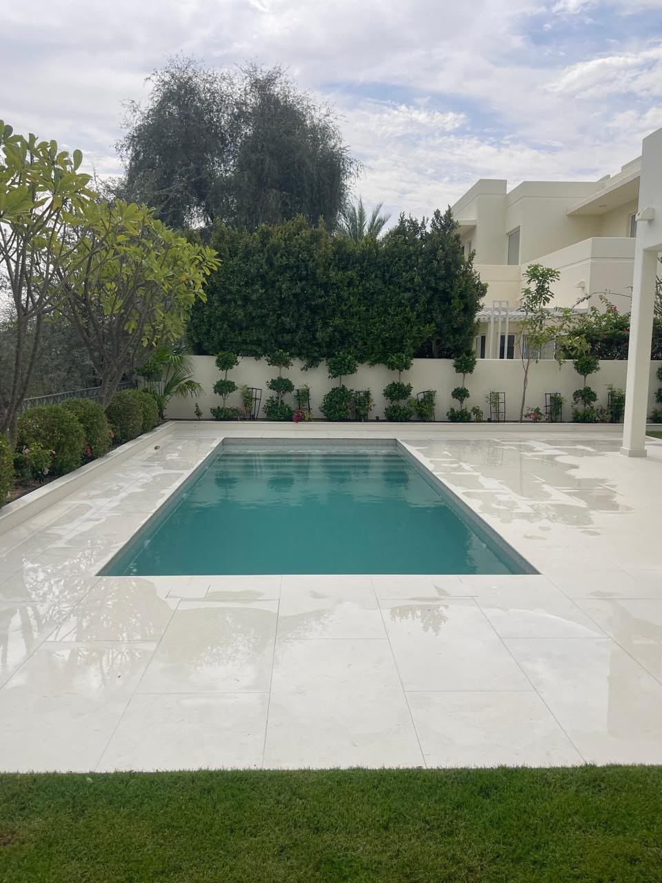 Finished swimming pool with white deck and lawn, villa garden